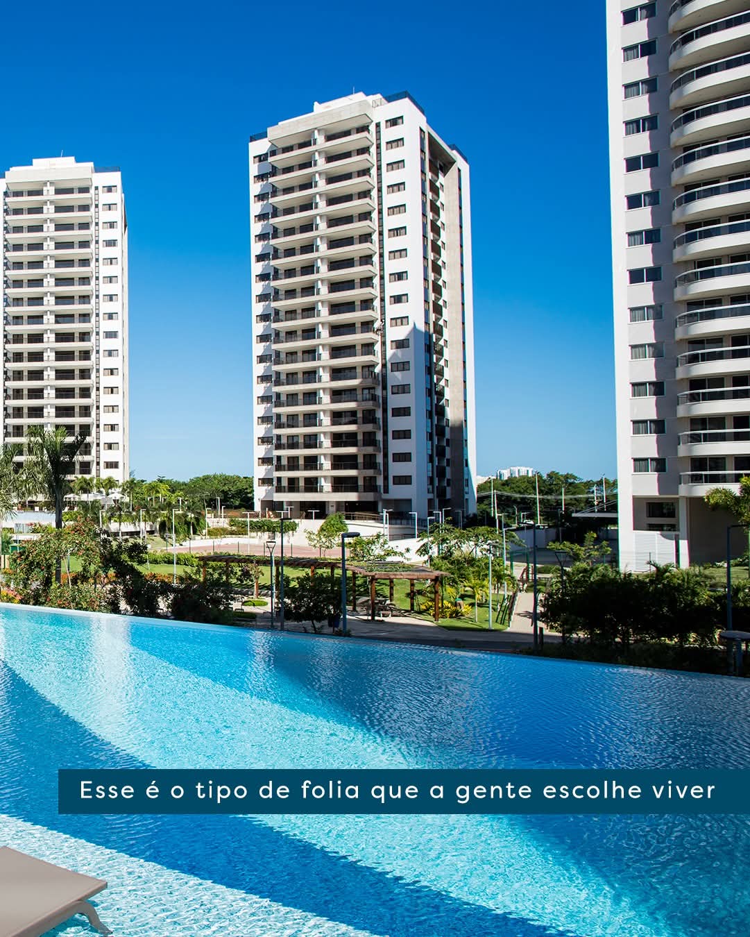 piscina de borda infinita com edifícios residenciais altos ao fundo sob céu azul — texto: Esse é o tipo de fo